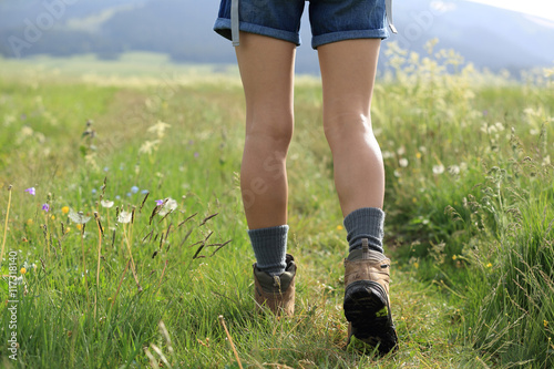 young woman hiker walking on trail in grassland