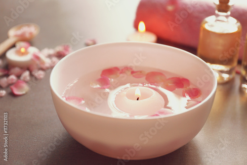 Petals on bowl with candle on grey background