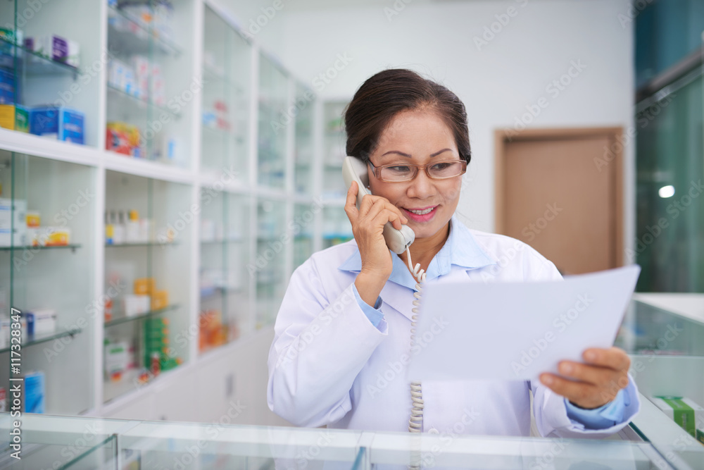 Drugstore worker ordering medication on the phone Drugstore worker ordering medication on the phone