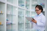 Female pharmacist with digital tablet searching for medication