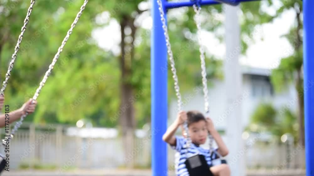 Two young Thai boy play a iron chain swinging at the playground under the sunlight in summer Two young Thai boy play a iron chain swinging at the playground under the sunlight in summer