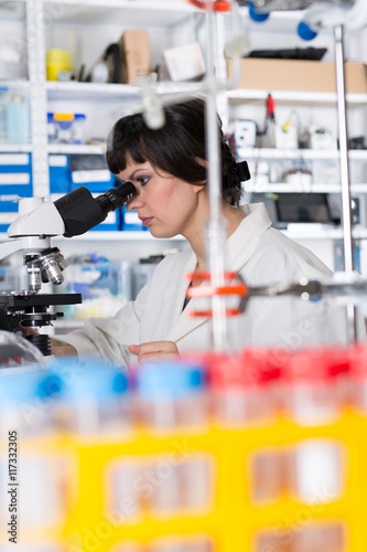 Young woman student work in microbiological laboratory with microscope