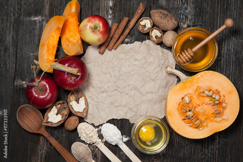 Ingredients for pumpkin and apple pie. Apples, nuts, pumpkin, honey, flour, eggs, oatmeal, sugar on vintage wooden background.