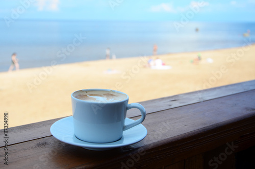 Close up of coffee cup on cafe terrace and the view on the sea in sunny day. Concept for relax, vacation or summertime.