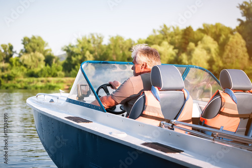 Mature man driving motor boat.