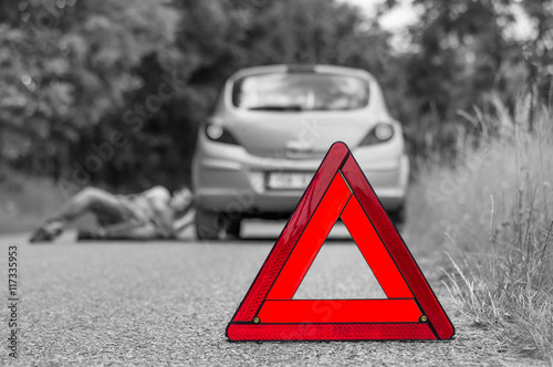 Driver lying under the broken car and red triangle