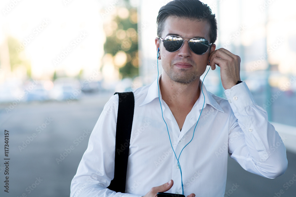 handsome young man with smartphone and headphones listen music