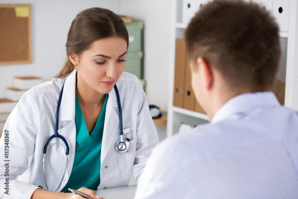Female doctor writing prescriptionto her male colleague or pati Female doctor writing prescriptionto her male colleague or pati