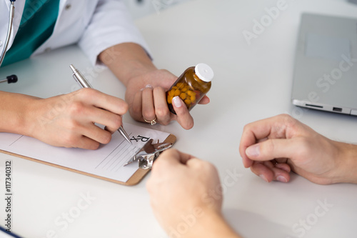 Close-up view of female doctor hand holding bottle with pills photo