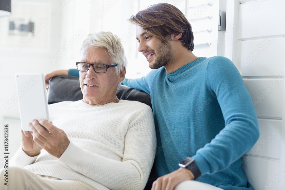 Happy father and son using digital tablet in living room Happy father and son using digital tablet in living room