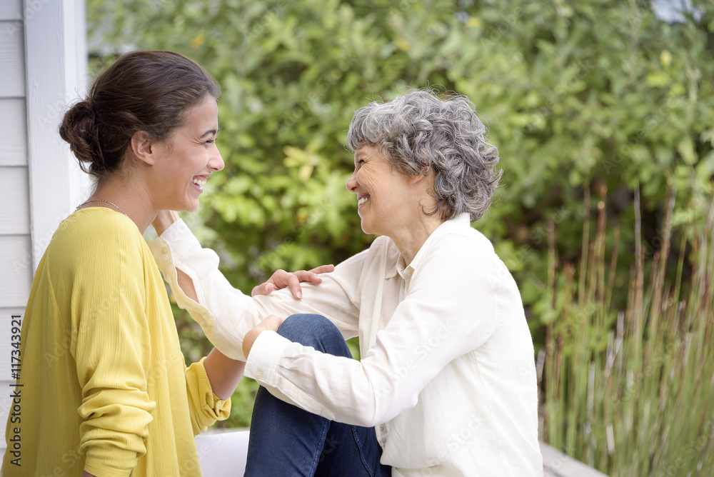 Happy mother talking with her adult daughter on porch Happy mother talking with her adult daughter on porch