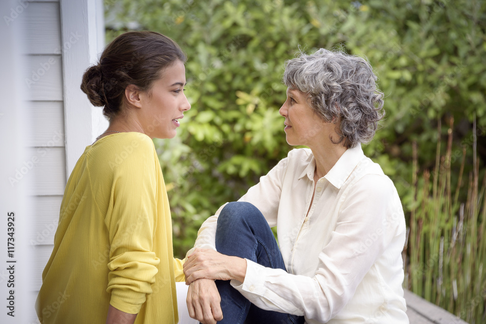 Happy mother talking with her adult daughter on porch Happy mother talking with her adult daughter on porch