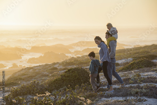 Happy young family walking on the beach at sunset