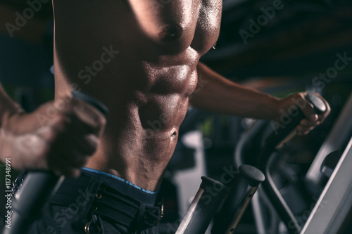 Photos Young man exercising in the gym on the elipsoid stepper