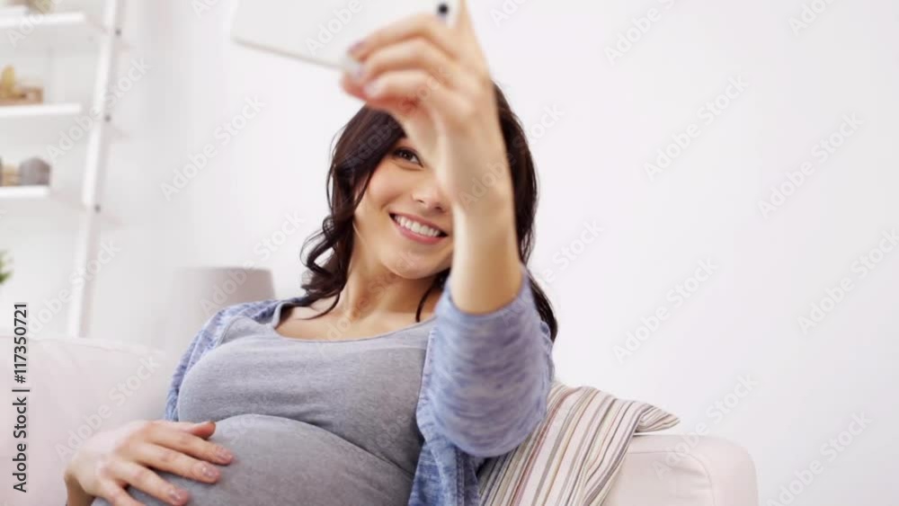 pregnant woman taking selfy by smartphone at home pregnant woman taking selfy by smartphone at home