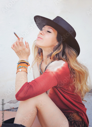 Beautiful woman enjoy smoking a cigarette, outdoor photo,  dressed in boho chic style outfit