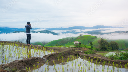 young photographer tacking photo in rice field morning