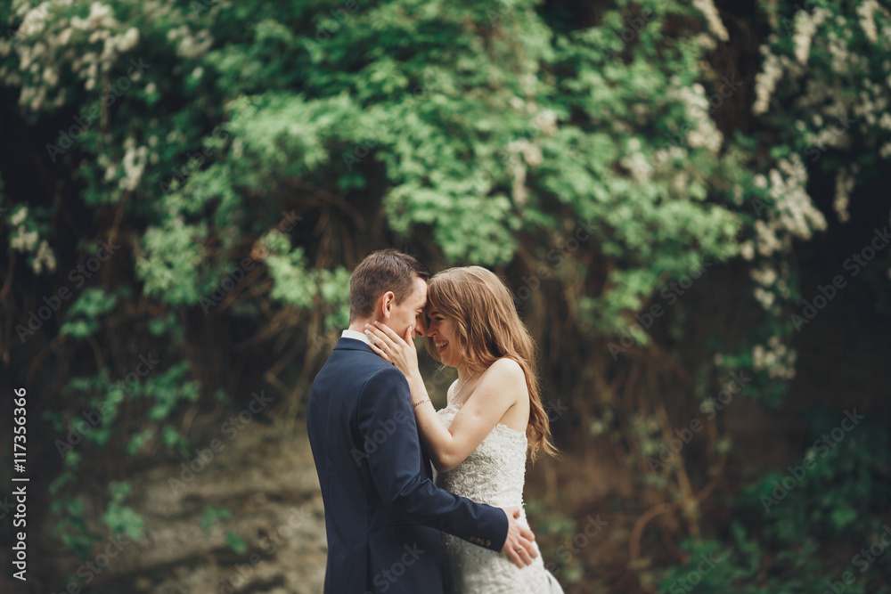 Happy wedding couple hugging and smiling each other on the background gorgeous plants in castle Happy wedding couple hugging and smiling each other on the background gorgeous plants in castle