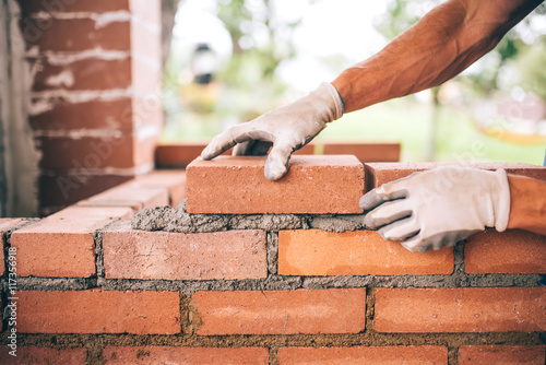 professional construction worker laying bricks and building barbecue in industrial site. Detail of hand adjusting bricks photo
