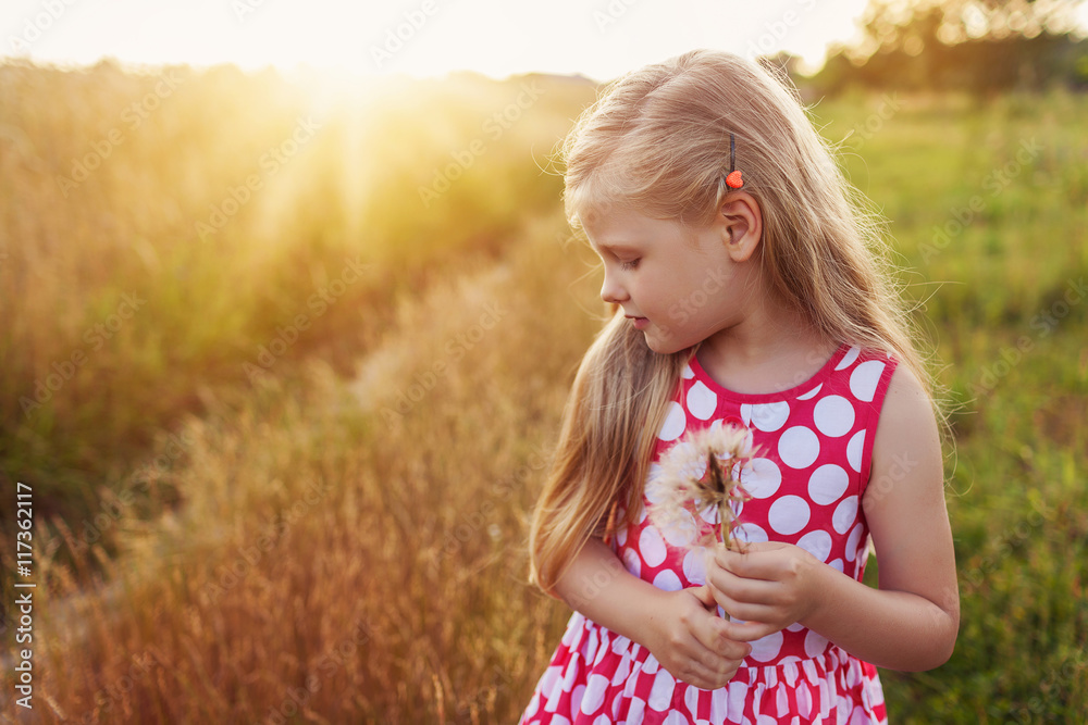 Little girl with dandelion on a meadow in the sunset. Little girl with dandelion on a meadow in the sunset.