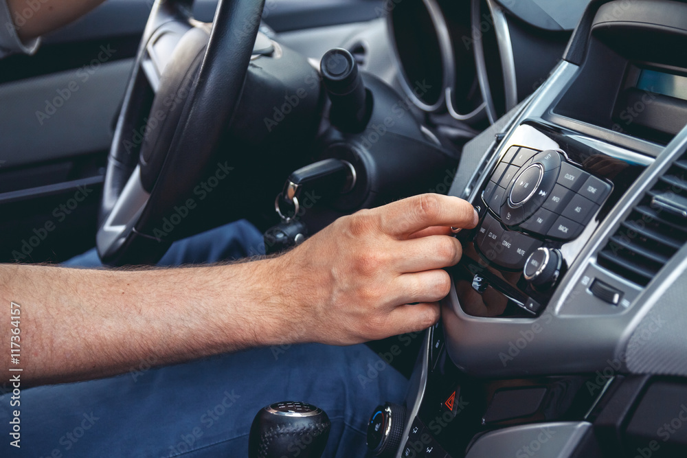 Naklejka premium Car dashboard. Radio closeup. Man sets radio