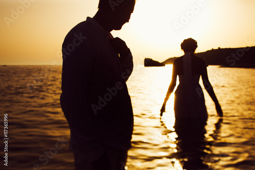 Man looks at a bride while she goes down in a sea water facing t
