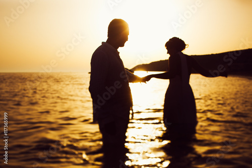 Silhouettes of a couple holding each other hands and standing in