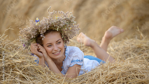 young girl in a wreath resting in straw haystack