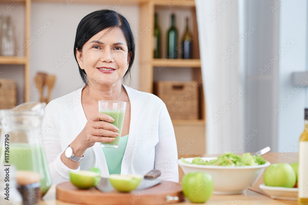 Portrait of mature Asian woman with glass of fresh smoothie Portrait of mature Asian woman with glass of fresh smoothie