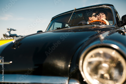 A look from the car's lights at newlyweds kissing on the front s