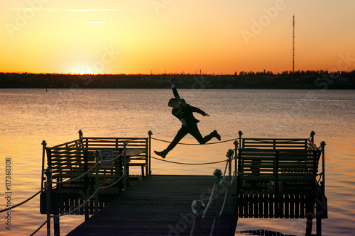 Happy man jumps up on the bridge on a estuary shore