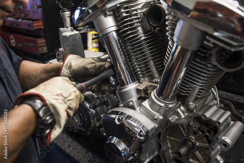 Close-up of mechanic fixing motorbike motor photo