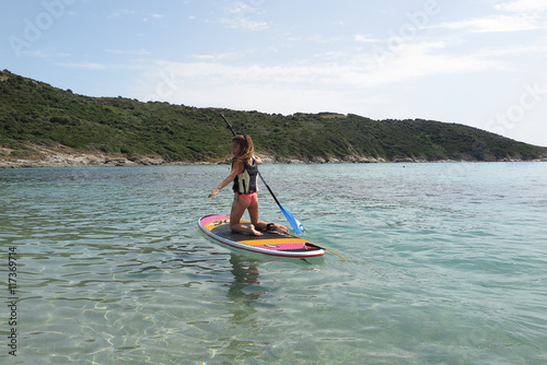 Beautiful and happy young girl learning paddle-surf