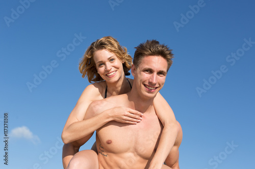happy young couple on the beach on a piggy back ride