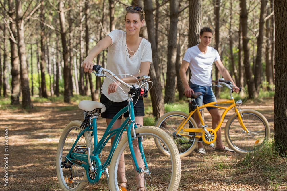 young couple with bicycle in forest