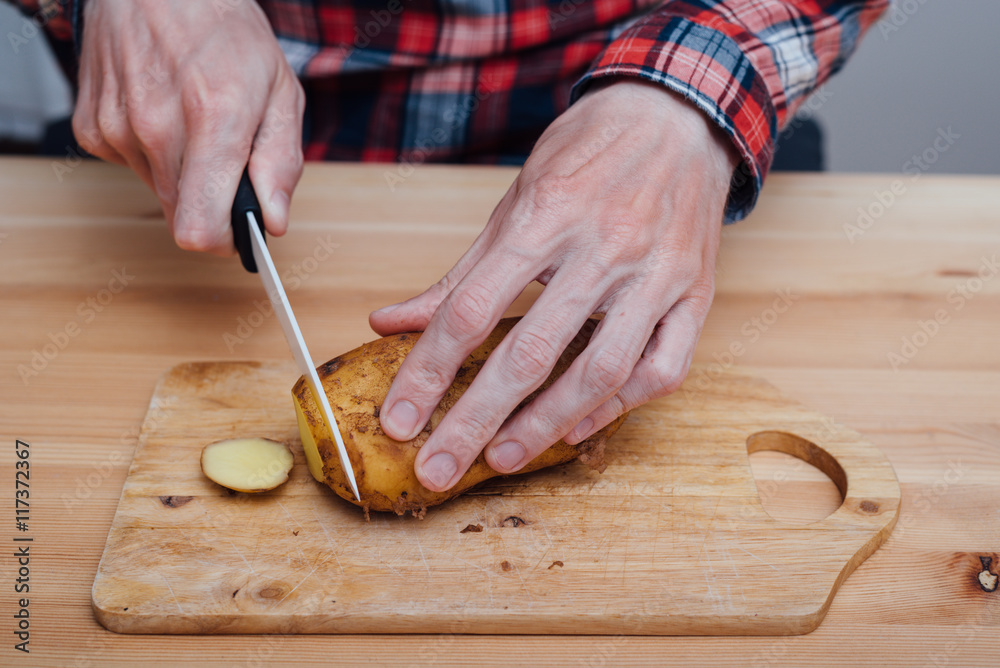 Man hands slicing fresh potato by ceramic knife