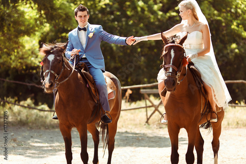 Groom and bride are riding horses together
