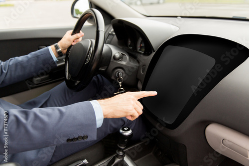 man driving car and pointing to on-board computer