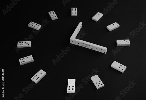 Dominoes in shape of clock on black background