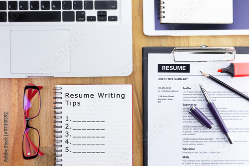 Businessman or HR Manager review a resume on his desk with computer laptop, digital tablet and glasses. With wording resume writing tips write on notebook. Flat lay.