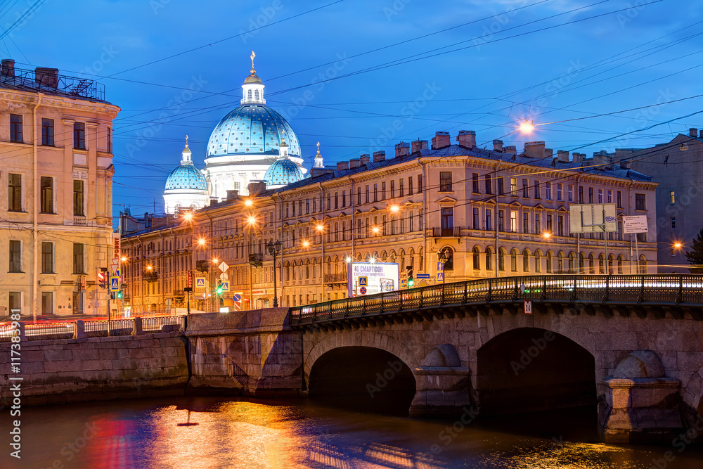 Night view of the Fontanka River, Izmailovsky Bridge and the dome of the Trinity Cathedral behind apartment buildings on Izmailovsky Prospect.