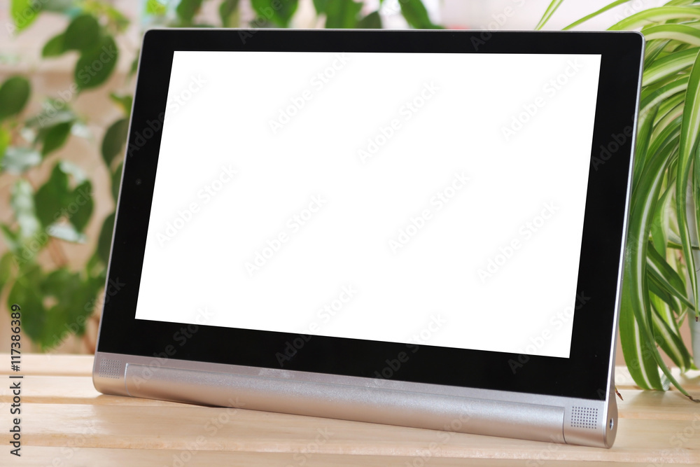 The tablet stands on wooden table on green background. Layout. The tablet stands on wooden table on green background. Layout.