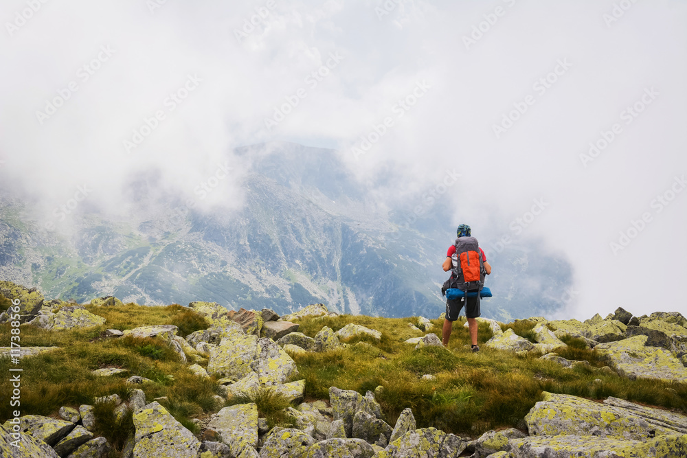 Young Man Traveler with backpack, admiring mountains.