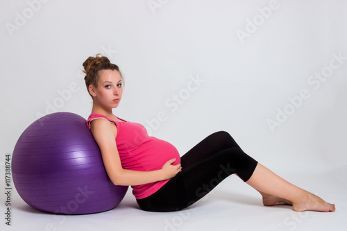 pregnant woman practicing yoga on a light background