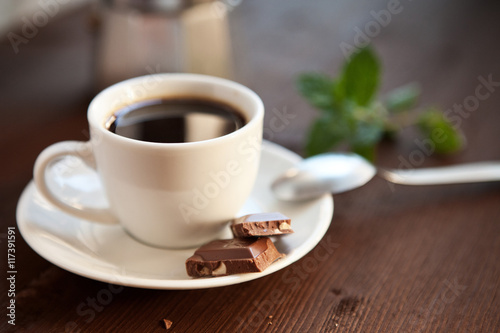 Filiżanka czarnej kawy z kostkami czekolady i listkiem mięty