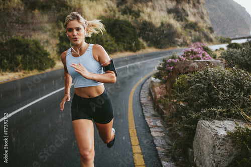 Fototapeta Female athlete running outdoors on highway