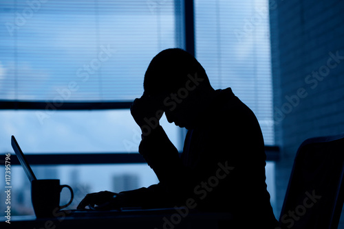 Stressed unhappy businessman working in dark office