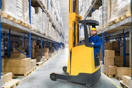 Young forklift driver in big distribution warehouse