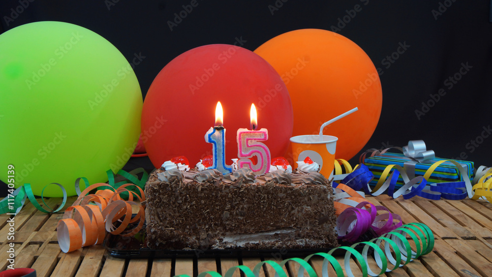 Chocolate birthday cake with candles burning on rustic wooden table ...