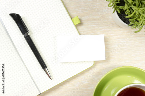 Business card blank, notepad, coffee cup and pen, flower at office desk table top view. Corporate stationery branding mock-up